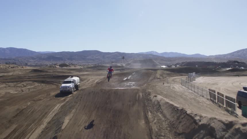 A motorcyclist jumps an obstacle on a dirt racing track