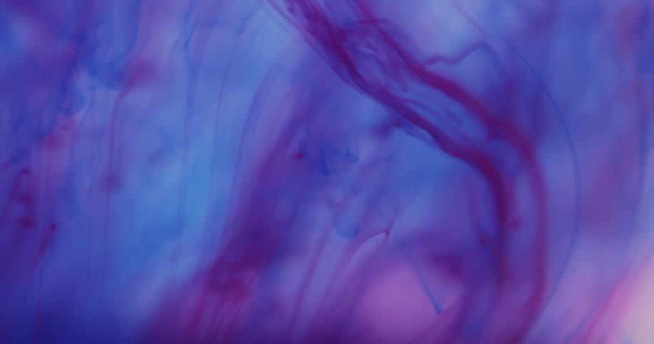 Blue and purple liquids are suspended in liquid and create a swirl pattern