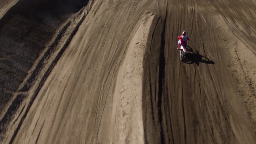 A motorcyclist rides a motorbike over a dirt track