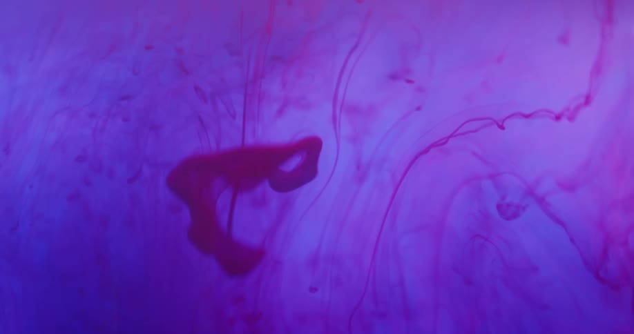 A red liquid disperses in a purple medium