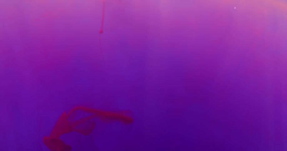 Red blobs of ink run and stretch against a backdrop of colors