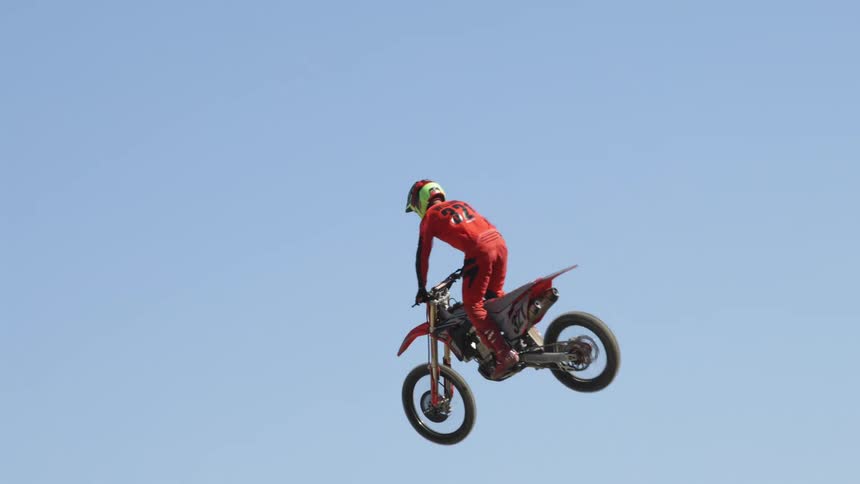 A motorcyclist jumps a dirt ramp on a racing track