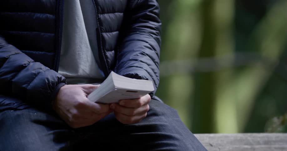 A man is reading a book outdodors