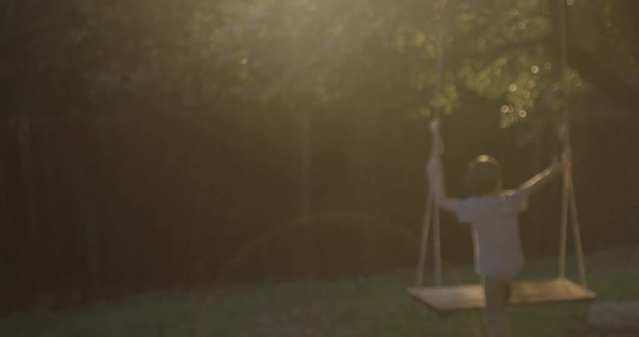 A young boy runs to play on a swing hanging from a tree