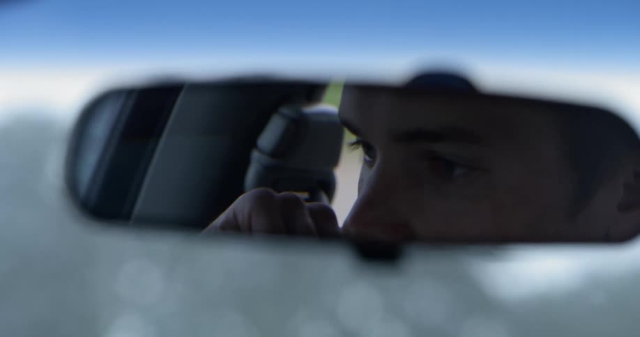 A mans eyes in his rear view mirror