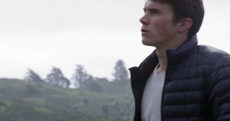 Close up of young man wearing a jacket hiking up a mountain
