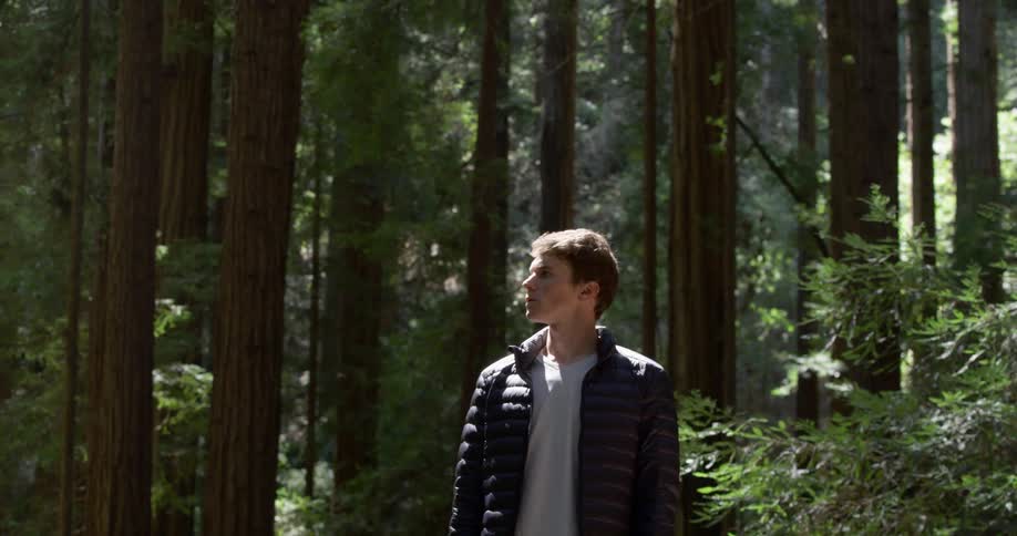 Man stands and looks around in the dense forest