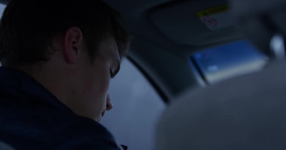 A young man sits in a vehicle and contemplates