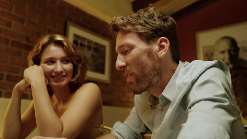 A man and woman are sitting and talking to someone in a room with a brick wall