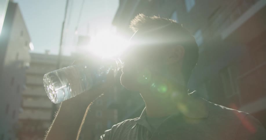 Man drinks a bottle of water in the neighborhood