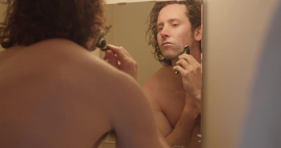 Man shaves with a razor in the bathroom