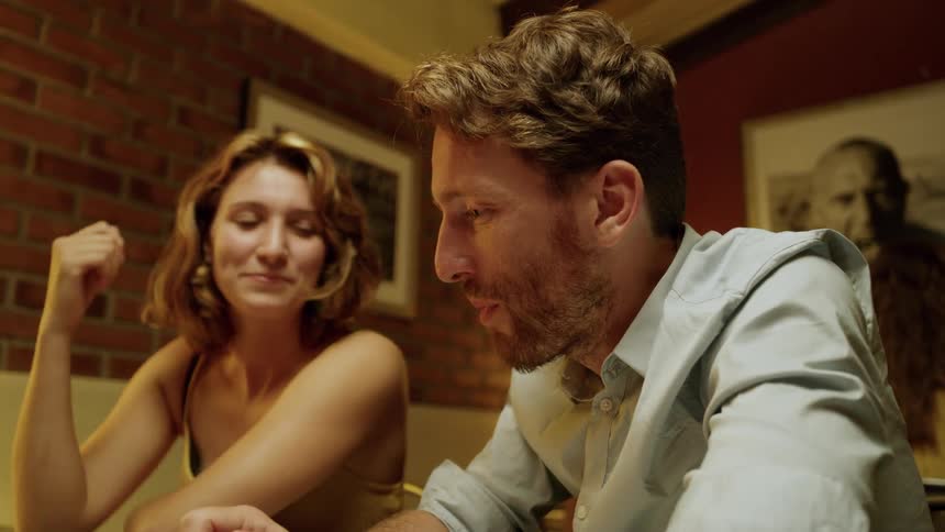 Man and woman sitting at the table talk to their friends in a cafe