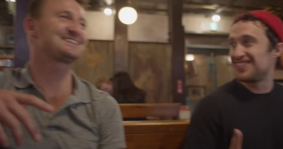 Two friends sitting at the table laugh and talk to each other in a cafe