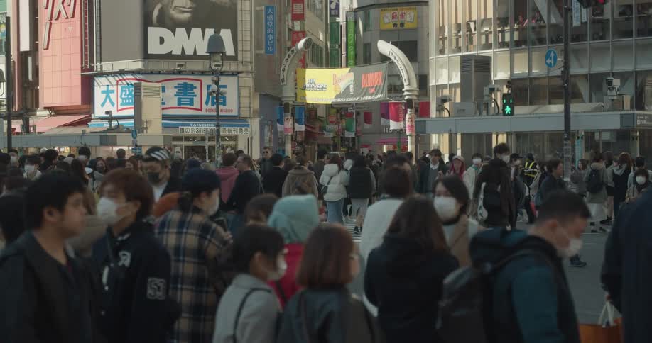 A large city with pedestrians wearing safety masks walking through downtown