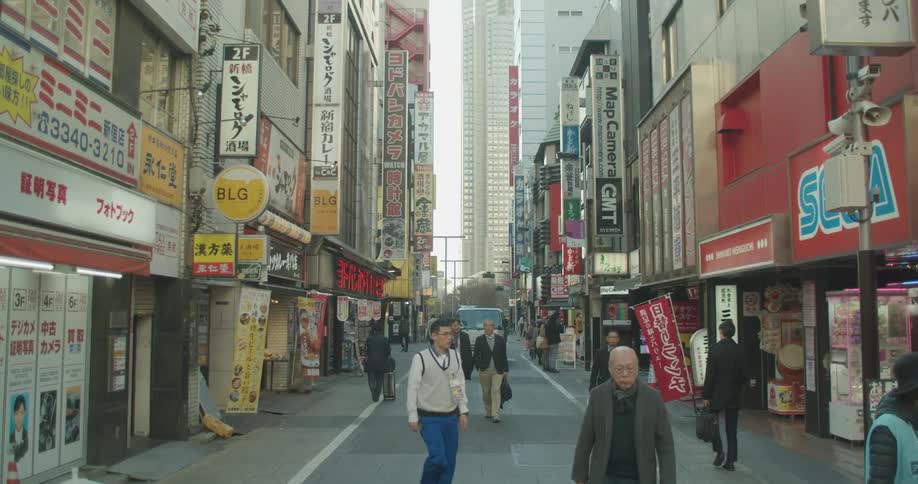 People walk past storefronts in a city