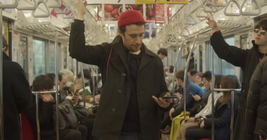 Man takes his cell phone out of his pocket as he travels on a city bus