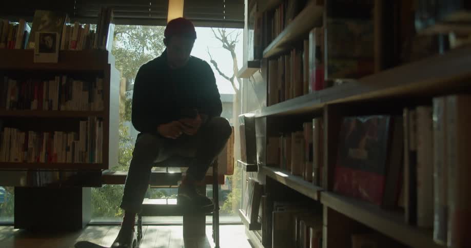 Man sitting in the chair uses his smartphone in the library