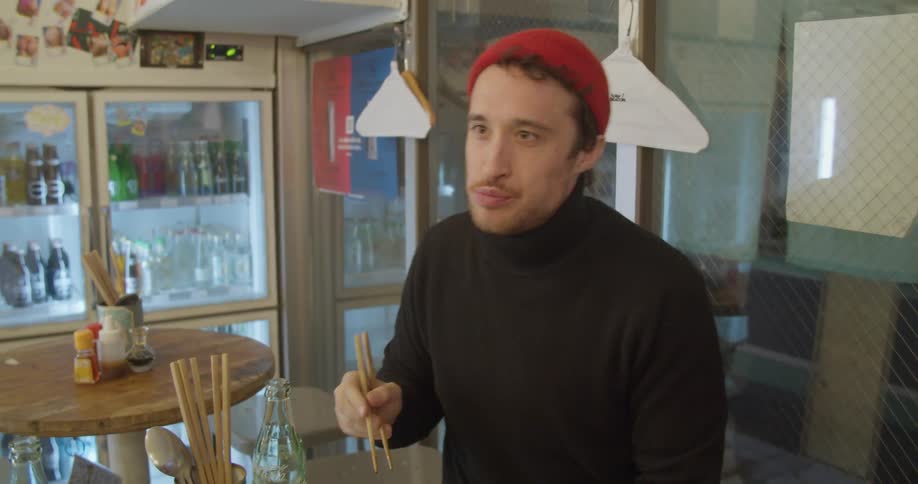Two men are eating with chopsticks in a diner