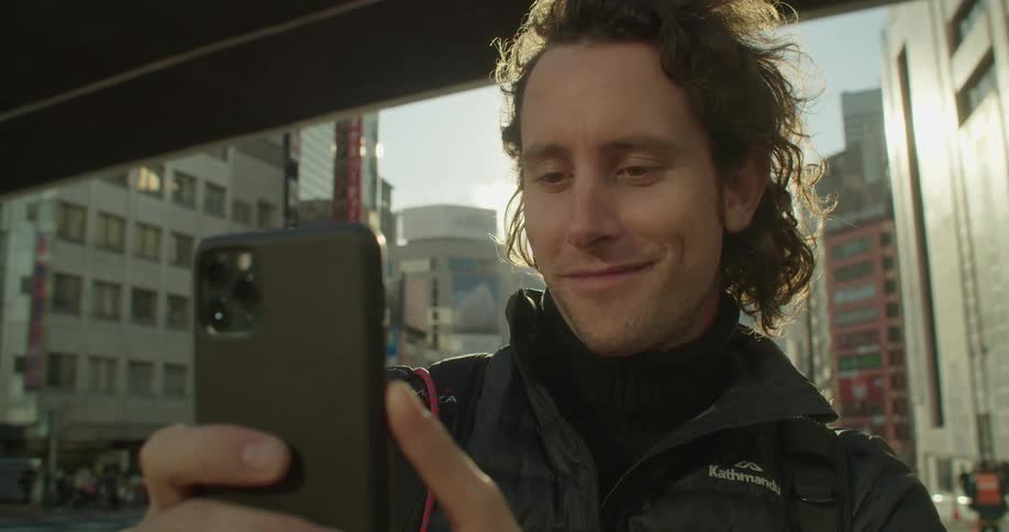 A man holds his phone up in a downtown area