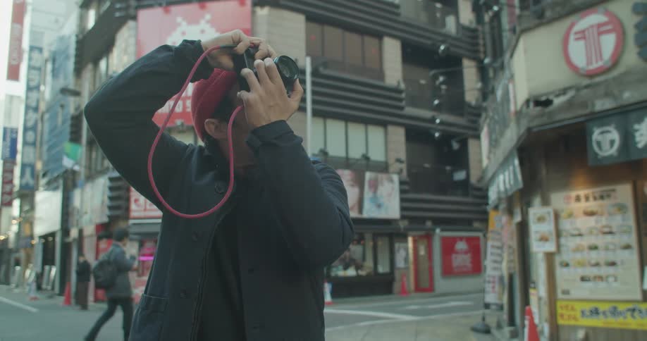 Man takes a picture of the buildings using a camera in the city