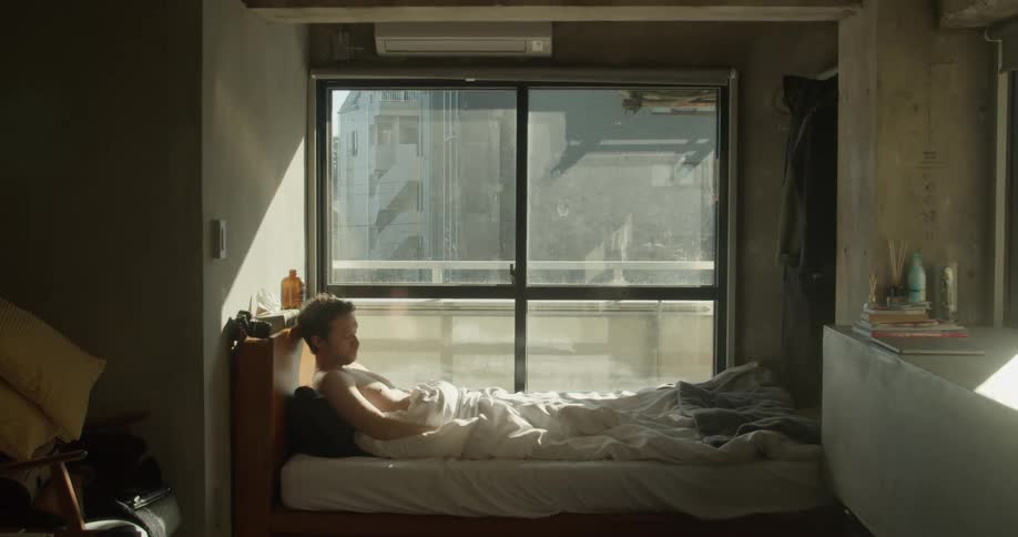 A man wakes up in bed and reaches over to grab his cell phone