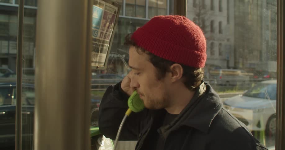A man makes on phone call on a public phone