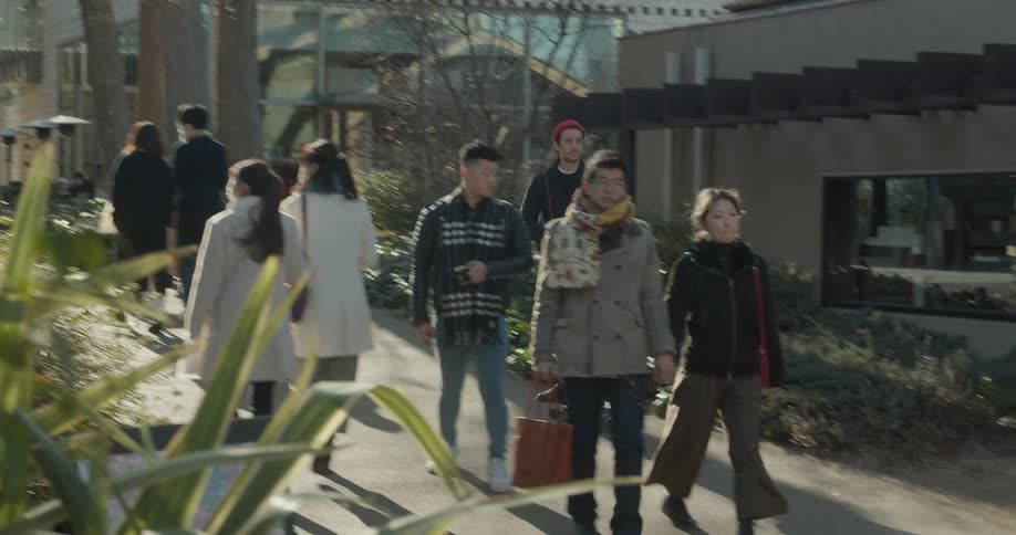 People walking as a man skates by them with a skateboard