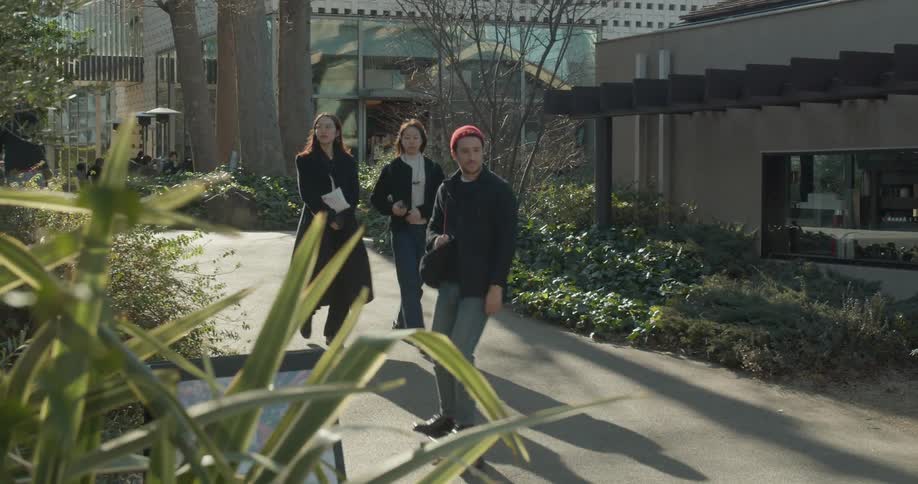 Man in red beanie skateboards past female pedestrians