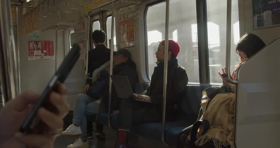 People use smart phones and laptops as they ride a train