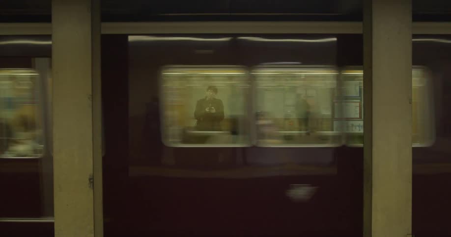 Several people are standing against the wall as a subway goes by