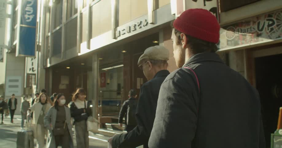 A middle eastern man walking down a street full of pedestrians in japan