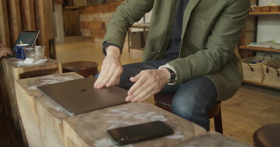 A man is sitting in a coffee shop with a laptop