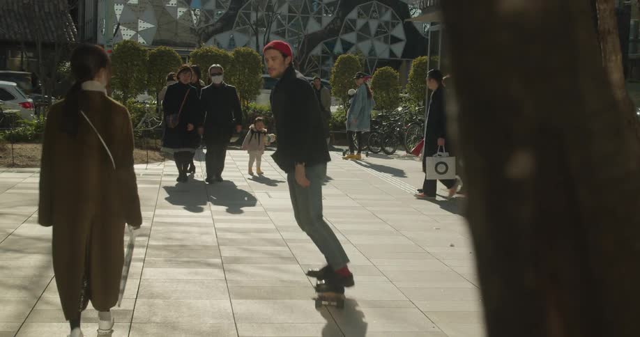 A man with a red hat riding a skateboard with people around him