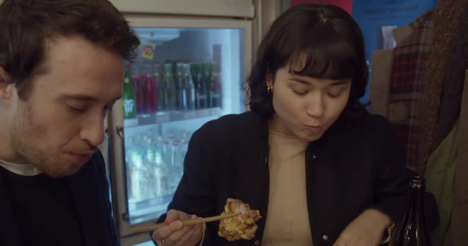 A man and woman eat food at a small table