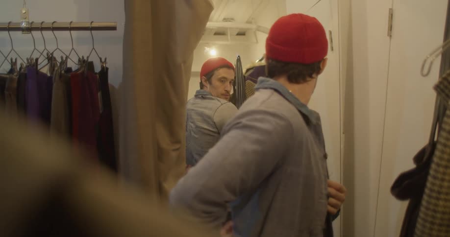 A man looks at himself in a mirror as he examines his shirt