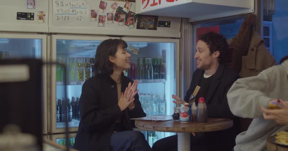 A man and woman sit at a table in a restaurant talking with each other
