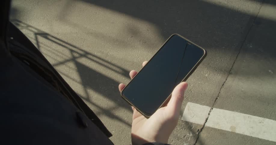 A person standing outdoors holding a smartphone