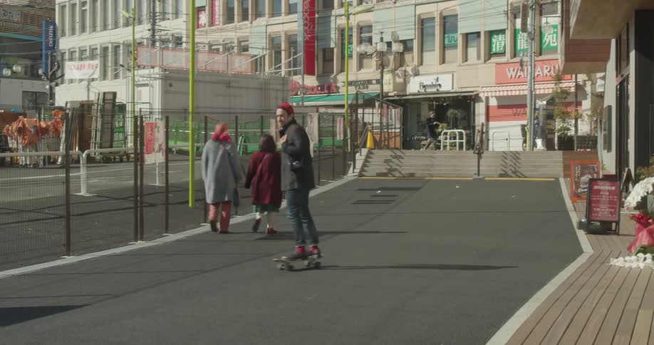 A man skateboards down a side city road beside a construction zone