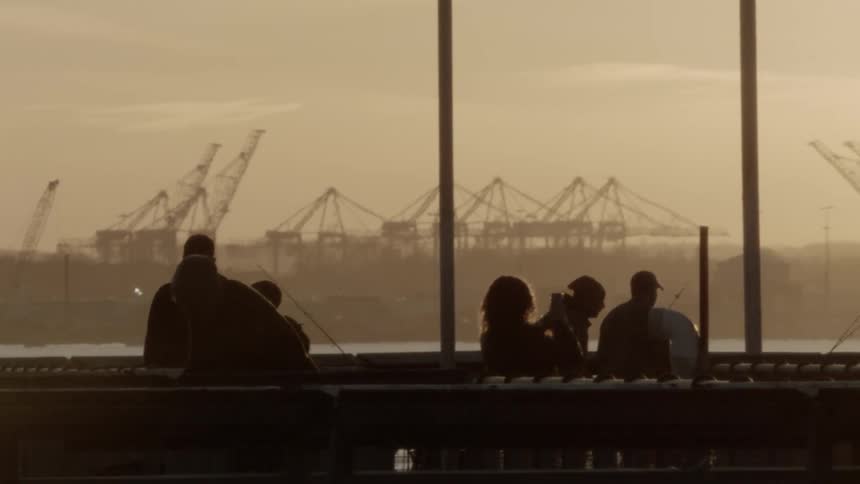 People fishing and relaxing on a pier at sunset