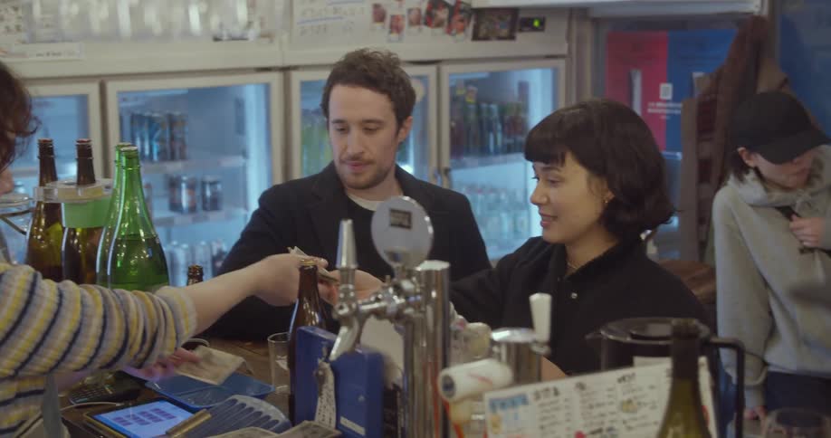 A man and a woman take part in a transaction at the counter of a restaurant