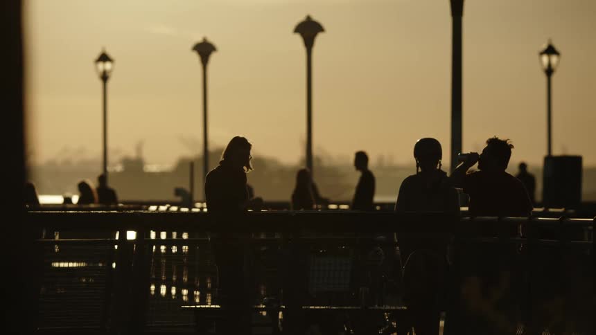 Several people are enjoying drinks while they stand near a body of water