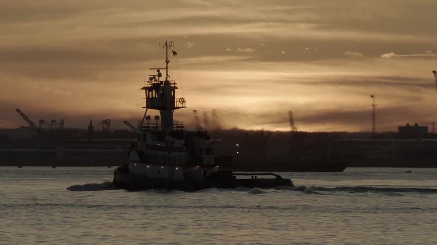 A boat sails across a body of water near a port