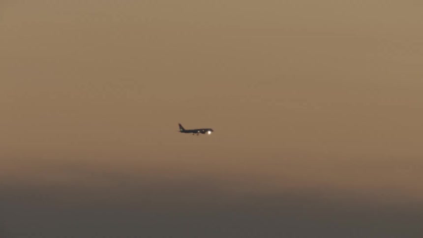 An airplane with its wheels down flies in the sky