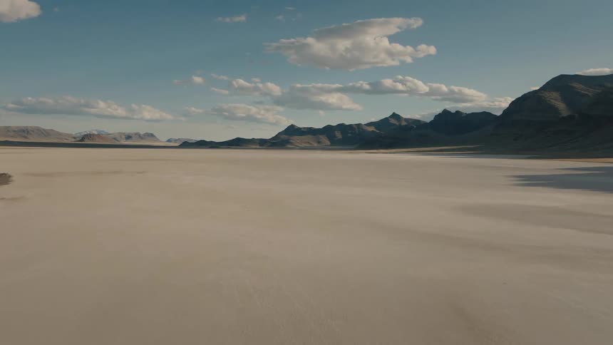 A desert expanse stretches in front of a mountain range