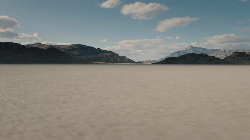 A mountain range looms in the background of a desert