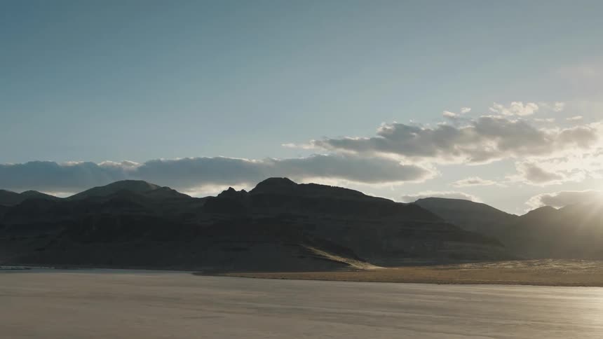 A flat desert area lies next to some mountains