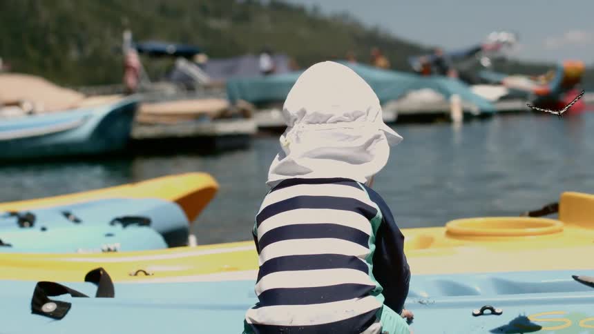 Child waits near canoe as butterfly flutters nearby