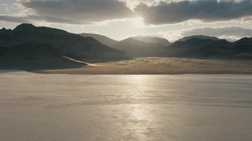 The sun rises over arid landscape by a mountain range
