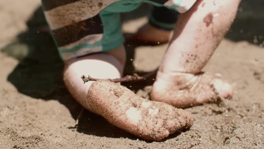 A white child covered in gritty soil and drops of water