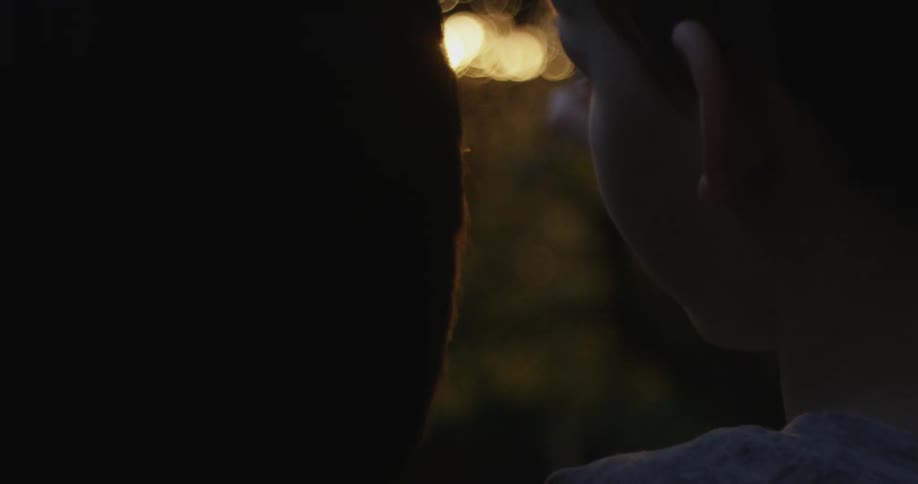 A woman is holding a child as they watch the sunset